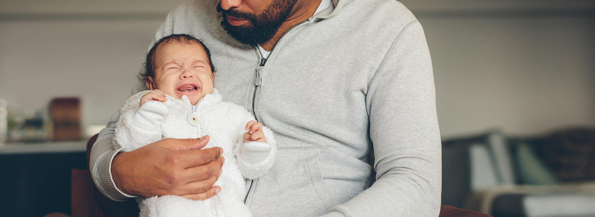 Crying baby held by father