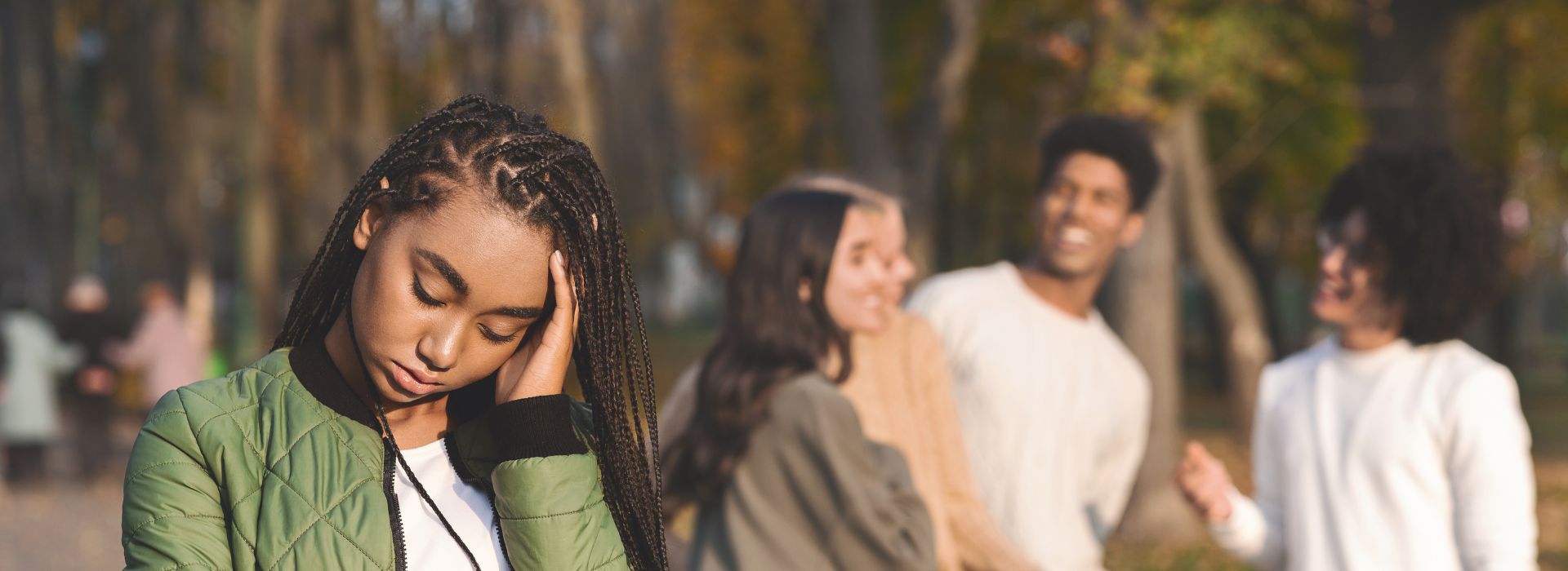 Sad teen with three other teens talking about her in the background