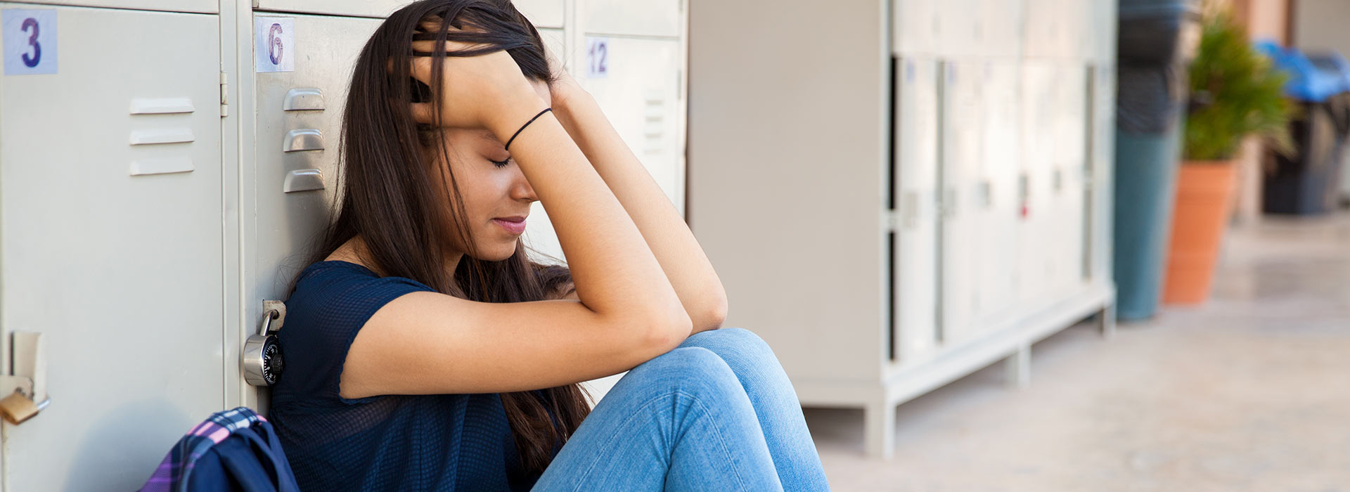 Stressed/upset teen sitting by lockers