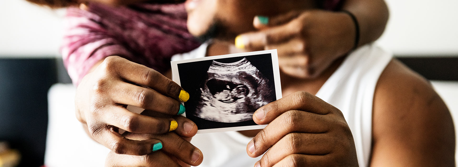 Couple in background holding ultrasound of baby together