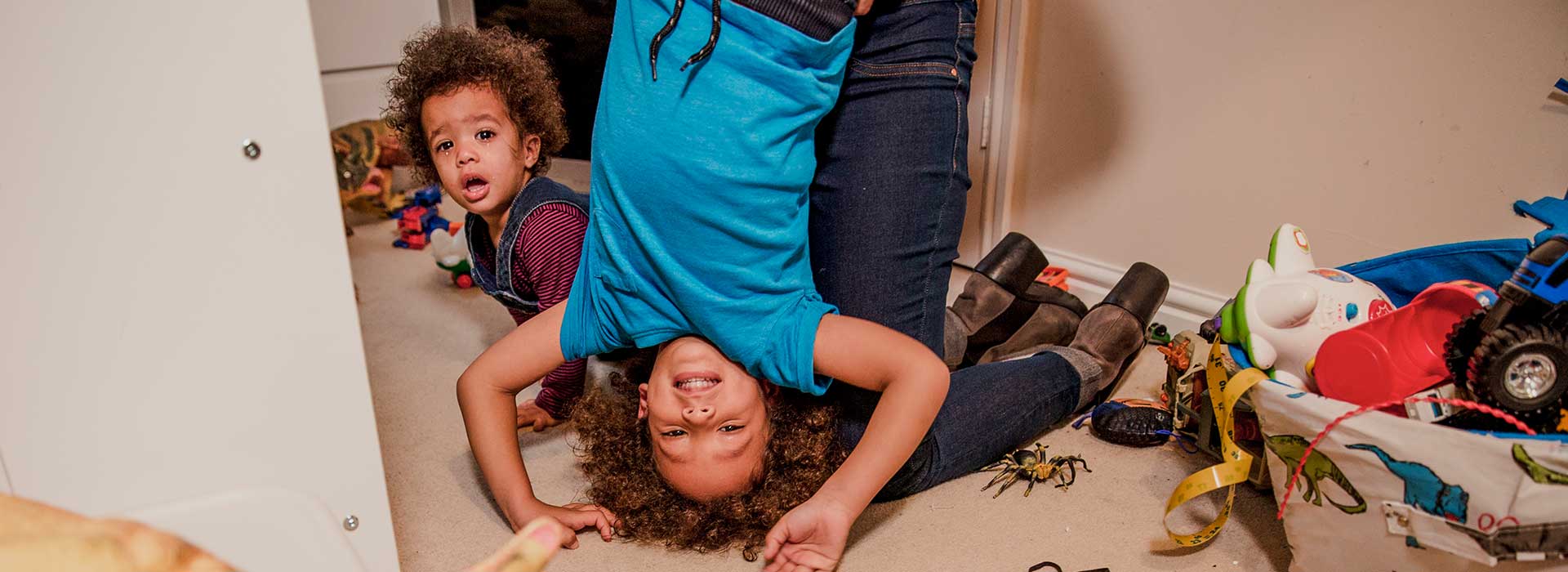 Two children playing with a parent in a messy room