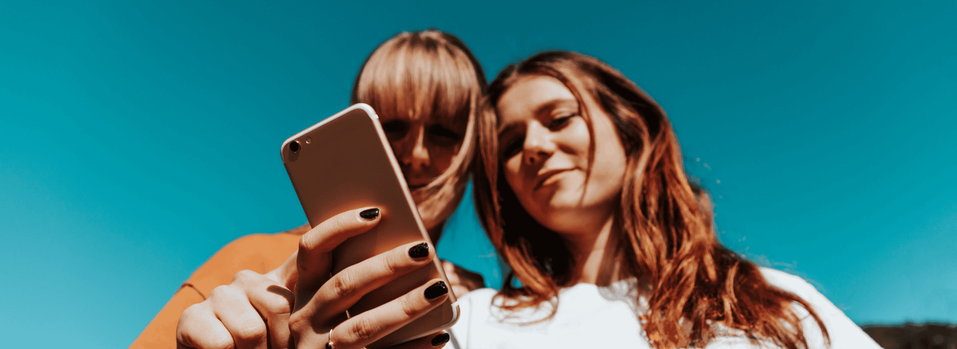 Two Teen Girls looking at a phone in their hand, scrolling social media