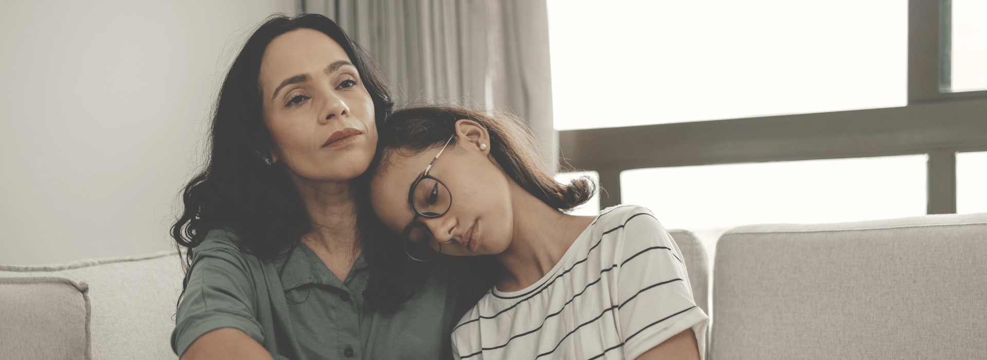 Sad tween hugging mum on the couch