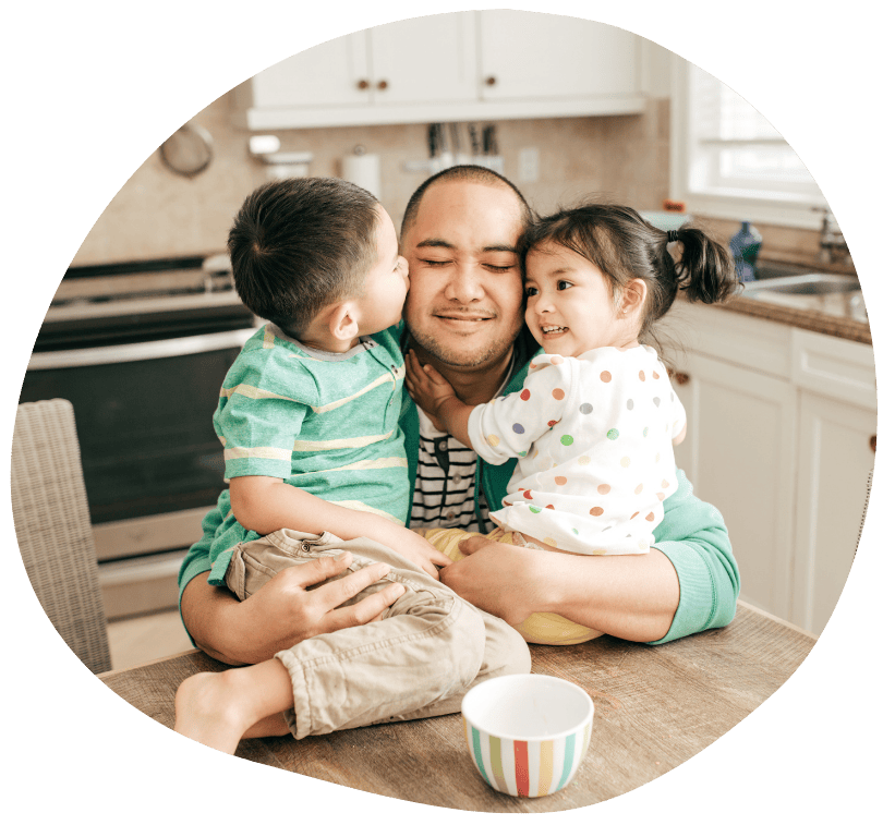A father holds his two young children in his arms. A father holds his two young children in his arms.