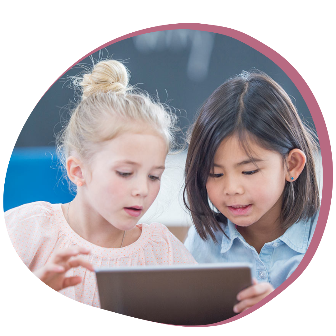 Two young girls look at an iPad together