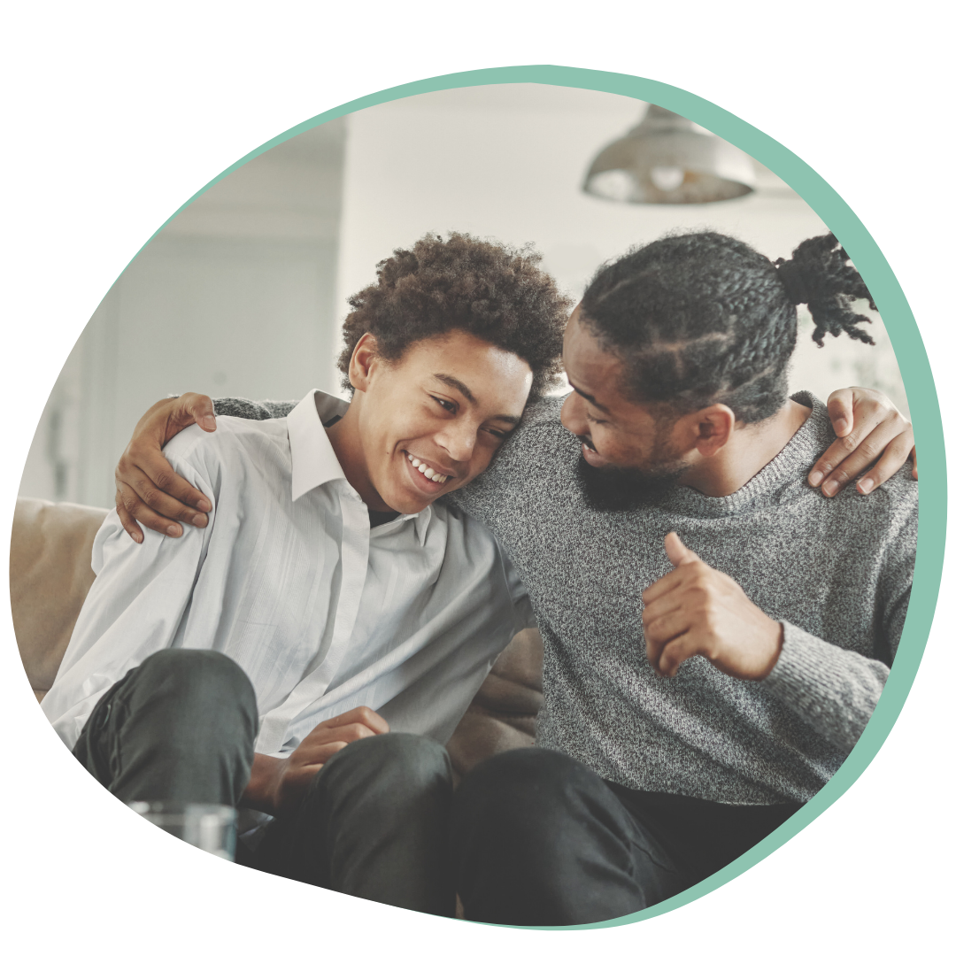 A Teenage Son and a Father embrace on a couch