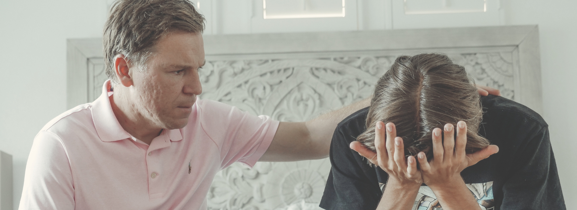 father consoles son on couch